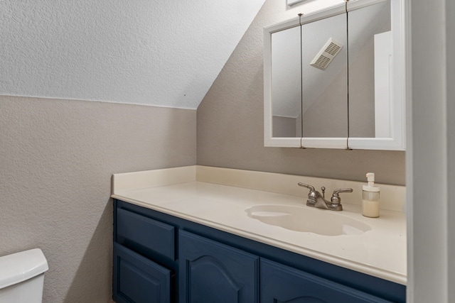 half bath with vaulted ceiling, a textured wall, vanity, and toilet