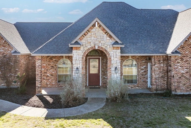 view of front facade featuring a shingled roof and brick siding