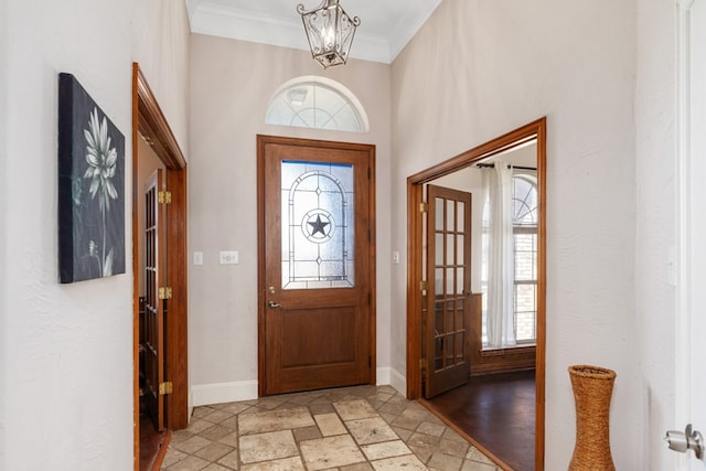 entrance foyer with baseboards, stone tile flooring, a wealth of natural light, and crown molding