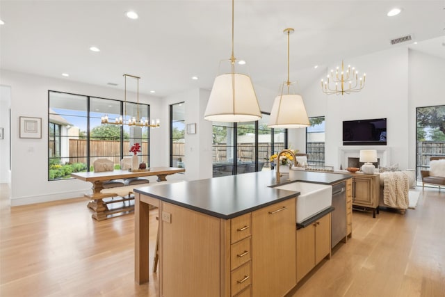 kitchen with a chandelier, light wood-style flooring, a center island with sink, and a sink