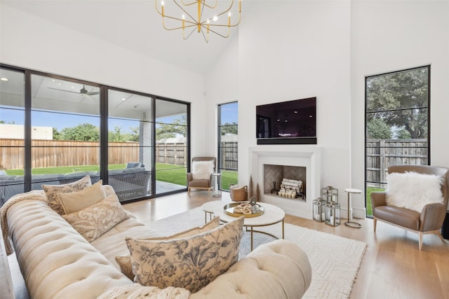 living area featuring high vaulted ceiling, a chandelier, wood finished floors, and a fireplace