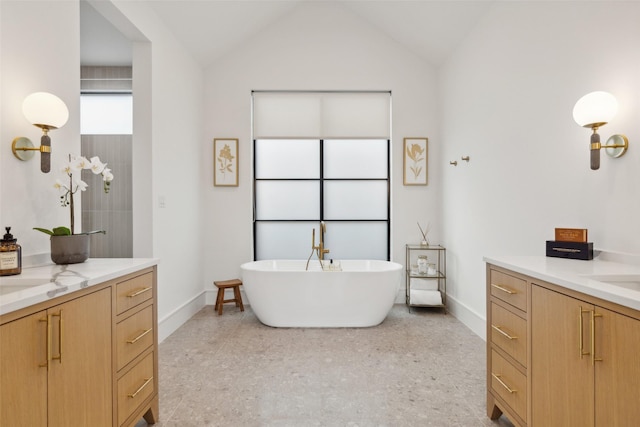 full bathroom with speckled floor, baseboards, a soaking tub, and two vanities