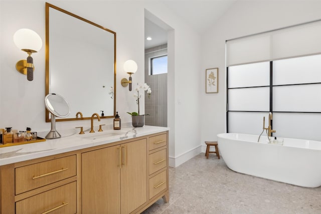 bathroom with vanity, baseboards, a soaking tub, and vaulted ceiling