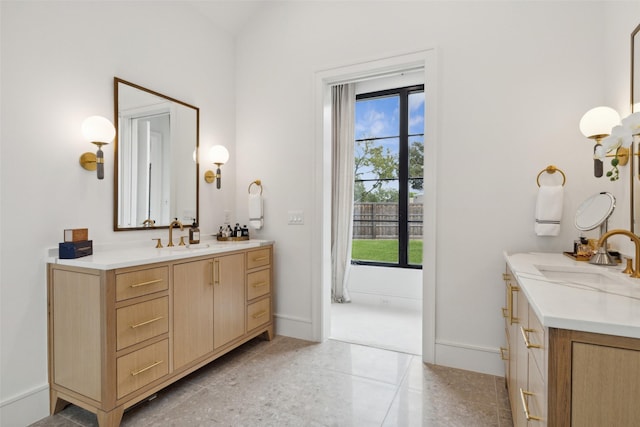 bathroom featuring two vanities, plenty of natural light, and a sink