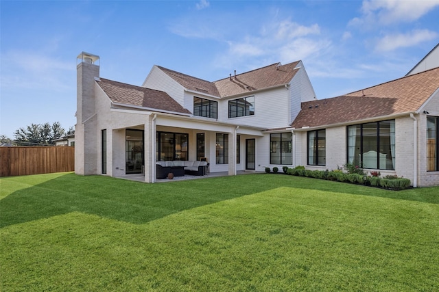 back of house featuring fence, outdoor lounge area, a chimney, and a yard