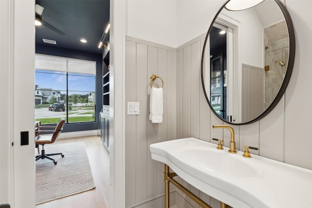 bathroom featuring visible vents, wood finished floors, a decorative wall, and a sink