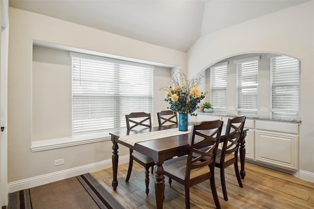 dining room with light wood-type flooring, lofted ceiling, and baseboards