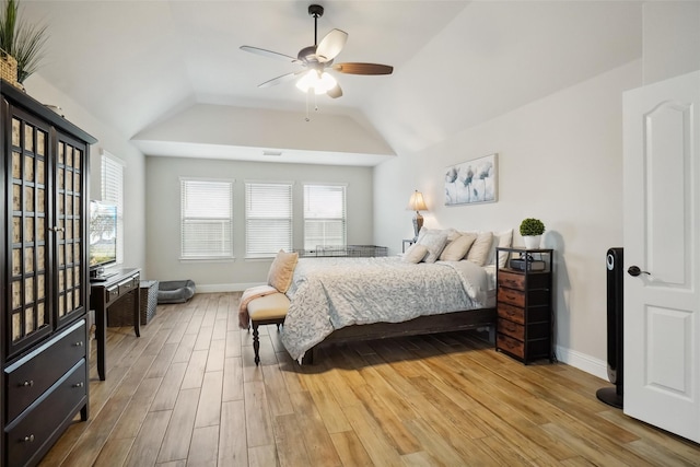 bedroom featuring multiple windows, lofted ceiling, baseboards, and wood finished floors