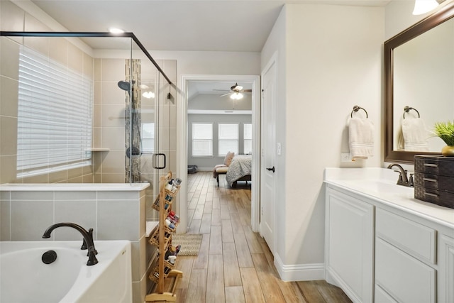 bathroom with wood tiled floor, a stall shower, connected bathroom, a bath, and vanity