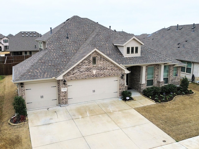 view of front of property with brick siding, fence, roof with shingles, a garage, and driveway