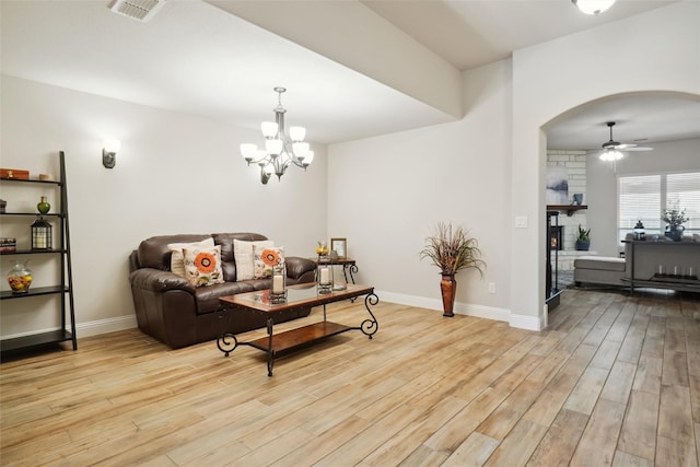 living room with baseboards, visible vents, arched walkways, light wood-style floors, and a large fireplace