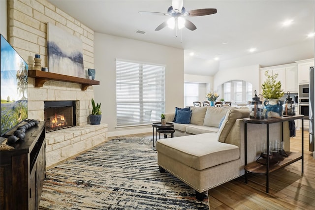 living room with wood finished floors, visible vents, recessed lighting, ceiling fan, and a stone fireplace