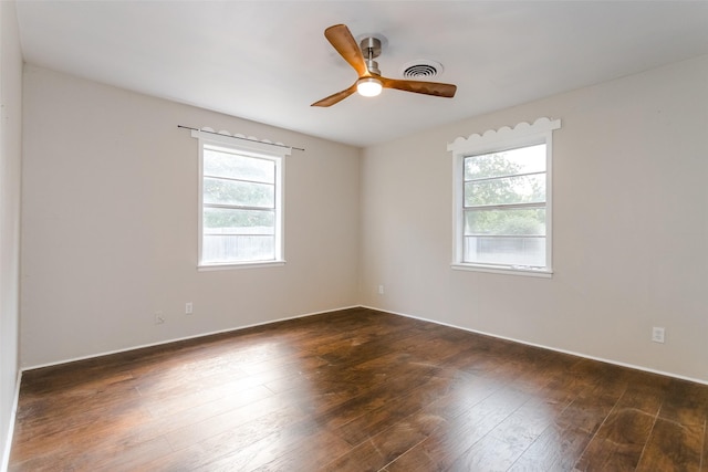 empty room with dark wood-style floors, ceiling fan, and visible vents