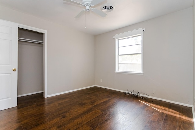 unfurnished bedroom with dark wood-type flooring, a closet, visible vents, and baseboards