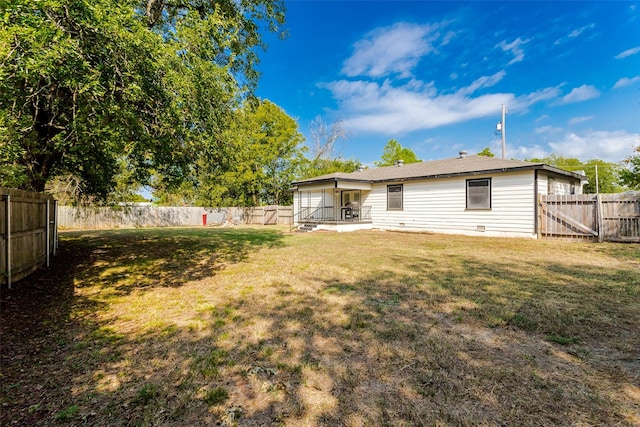 rear view of house featuring a gate, a fenced backyard, and a yard