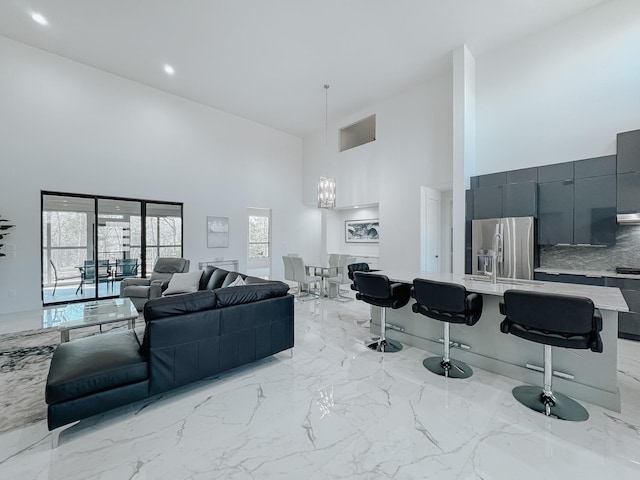 living area with marble finish floor, a towering ceiling, recessed lighting, and an inviting chandelier