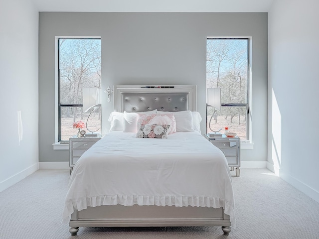 carpeted bedroom featuring baseboards and multiple windows