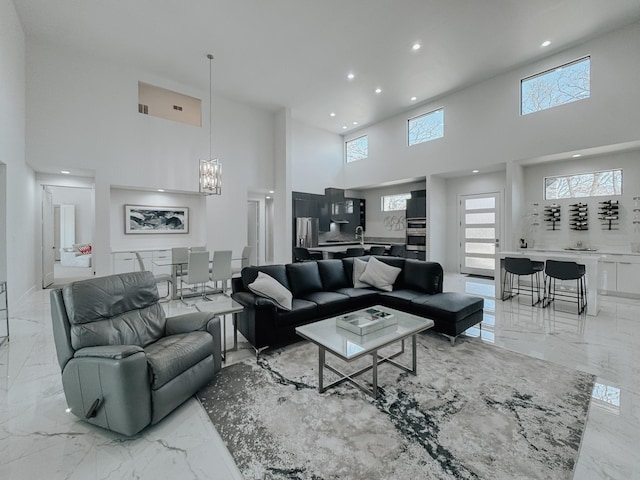 living area with a notable chandelier, marble finish floor, a high ceiling, and recessed lighting