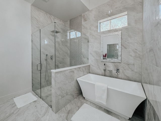 bathroom featuring a freestanding bath, a shower stall, marble finish floor, and tile walls