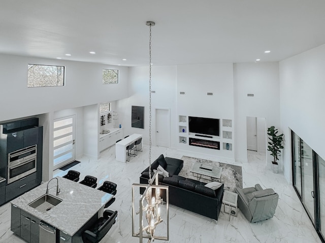 living area with visible vents, a high ceiling, marble finish floor, and recessed lighting