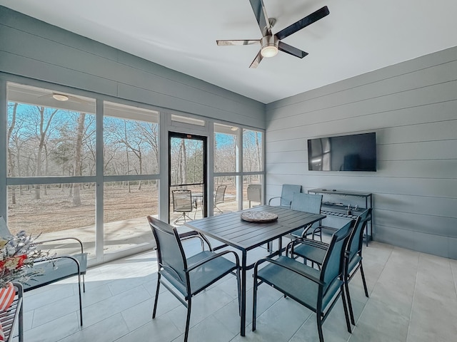 dining area featuring wooden walls, a ceiling fan, and light tile patterned floors