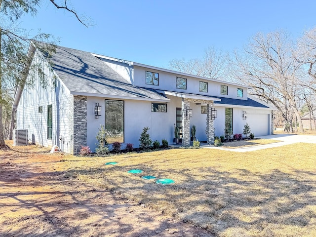 view of front of home featuring stone siding, an attached garage, a shingled roof, and central AC