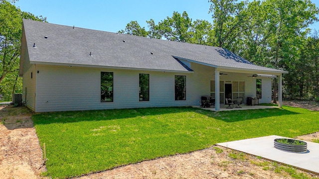 rear view of property featuring a patio area, a ceiling fan, a shingled roof, and a lawn