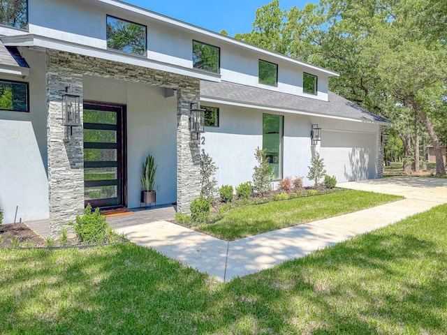 view of front of property with stucco siding, a front lawn, stone siding, and a garage