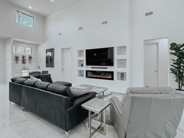 living room with visible vents, a high ceiling, built in features, and marble finish floor