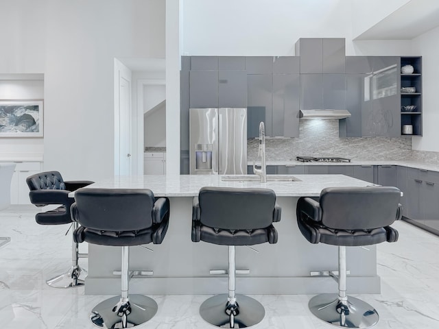 kitchen featuring tasteful backsplash, modern cabinets, gray cabinetry, a breakfast bar, and appliances with stainless steel finishes