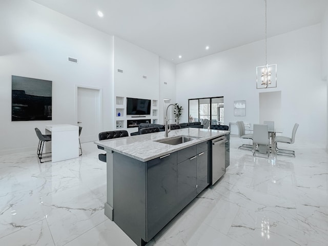 kitchen featuring a high ceiling, marble finish floor, stainless steel dishwasher, a sink, and gray cabinetry