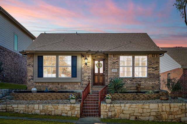 view of front of house with brick siding and roof with shingles