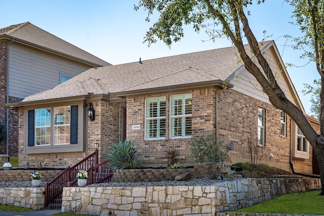 view of front of home with brick siding and roof with shingles