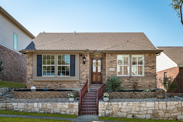 view of front of property with brick siding and roof with shingles