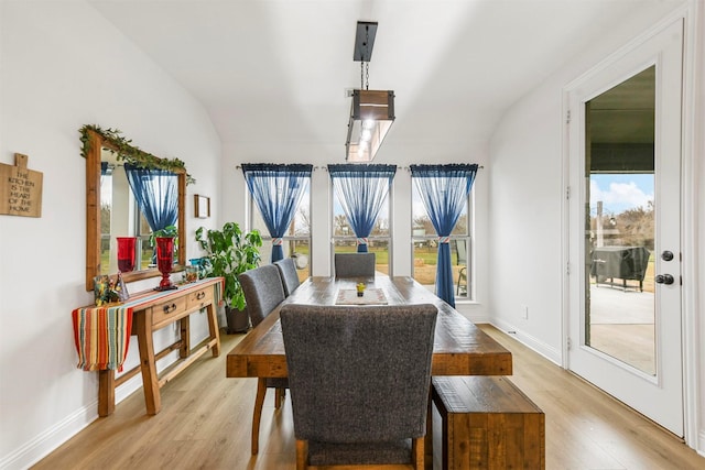 dining room featuring light wood-type flooring, lofted ceiling, and baseboards