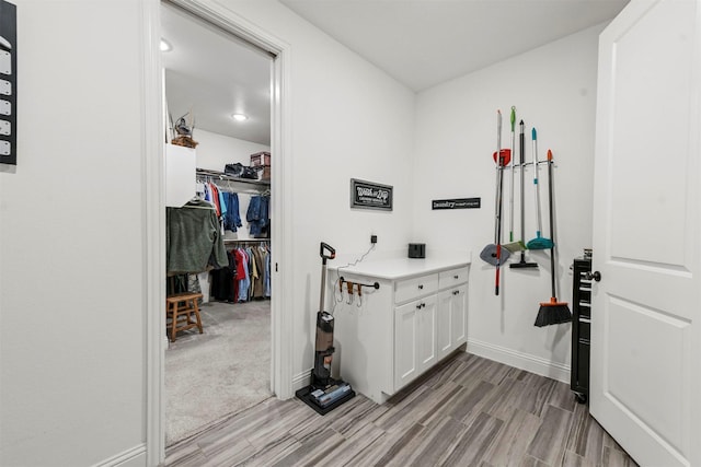 laundry area with light wood finished floors and baseboards