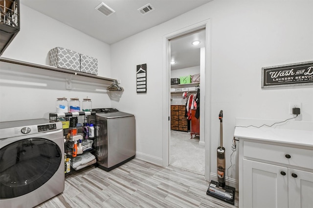 laundry area featuring separate washer and dryer, light wood-type flooring, visible vents, and baseboards