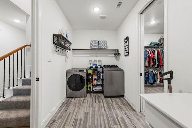 clothes washing area featuring laundry area, light wood-type flooring, visible vents, and washer and dryer