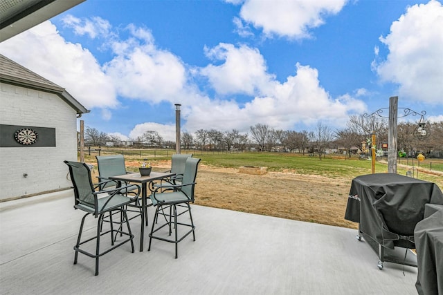 view of patio featuring outdoor dining space, a grill, and fence