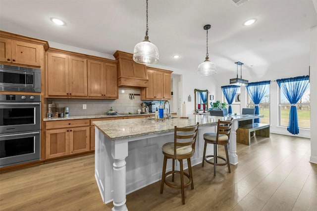 kitchen featuring light stone counters, appliances with stainless steel finishes, backsplash, and light wood-style flooring