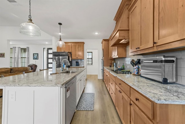 kitchen with stainless steel appliances, light wood-type flooring, a sink, and decorative backsplash