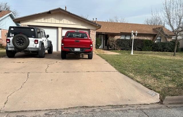 ranch-style house with driveway, an attached garage, a front yard, board and batten siding, and brick siding