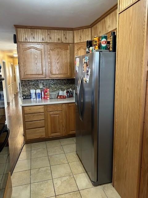 909 Harwell St, Abilene, TX 79601 - kitchen featuring light tile patterned flooring, light countertops, freestanding refrigerator, tasteful backsplash, and brown cabinetry