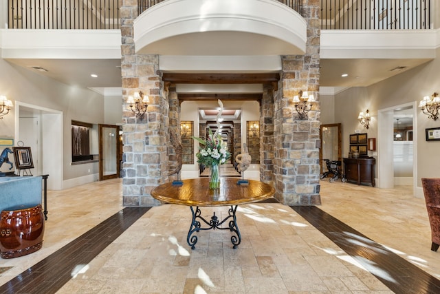 foyer with a towering ceiling, decorative columns, and wood finished floors