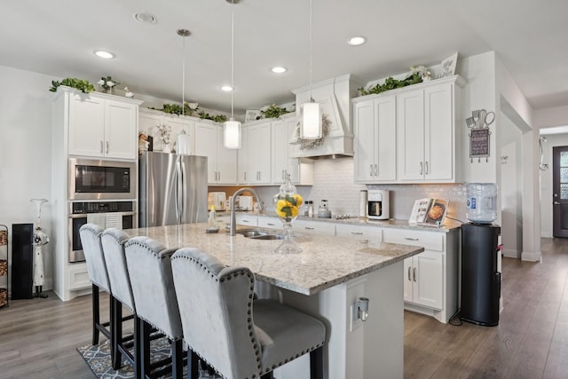 kitchen with a breakfast bar area, a sink, white cabinetry, appliances with stainless steel finishes, and decorative backsplash