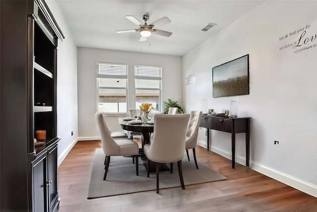 dining area with light wood-style floors, visible vents, baseboards, and a ceiling fan