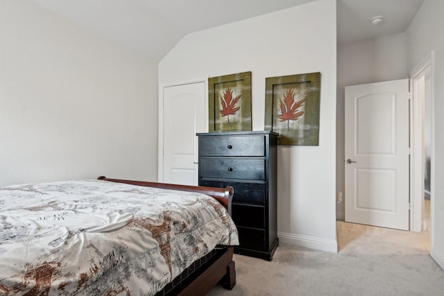 bedroom with light colored carpet, vaulted ceiling, and baseboards