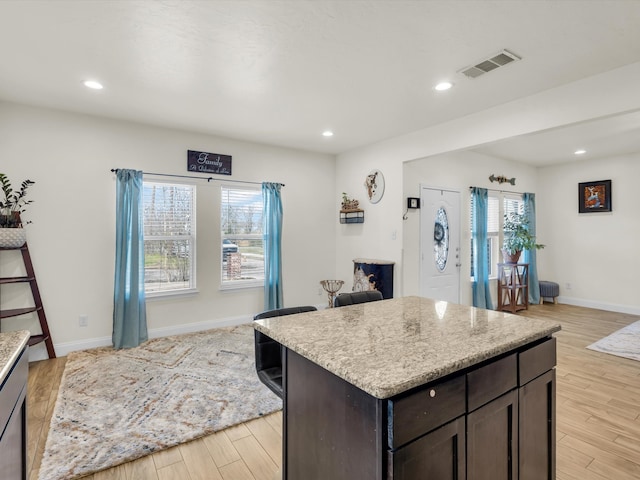 kitchen featuring visible vents, dark brown cabinets, light wood-type flooring, and a healthy amount of sunlight