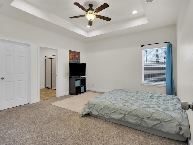 bedroom with recessed lighting, baseboards, a raised ceiling, and light carpet