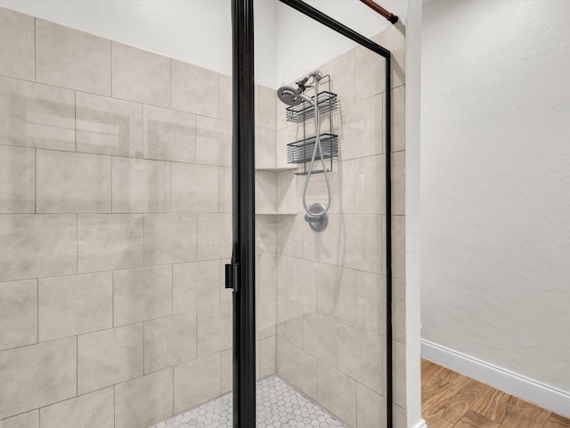 full bath with a shower stall, wood finished floors, and baseboards